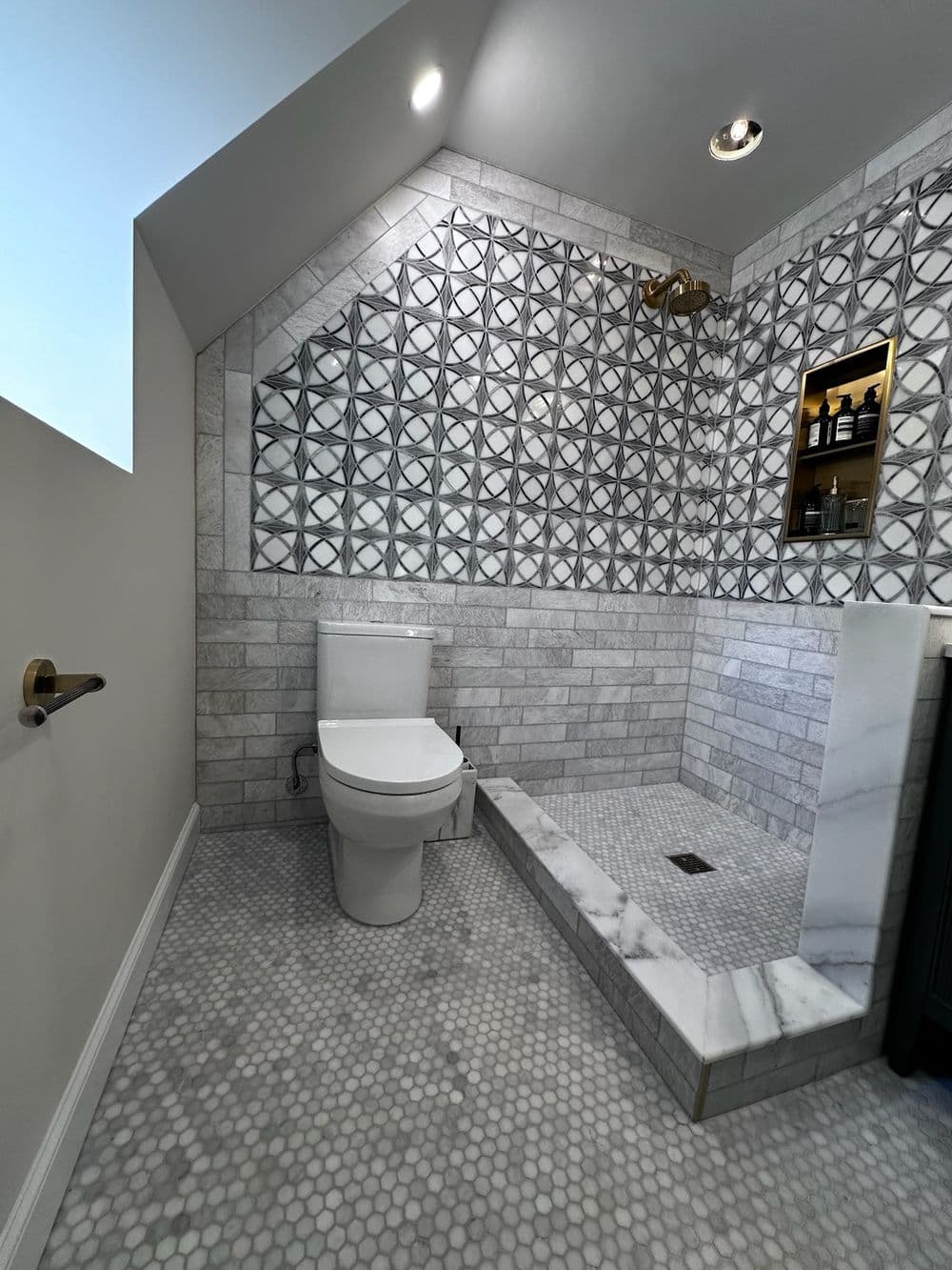 Modern bathroom design featuring a marble shower, geometric tiles, and a sleek toilet.
