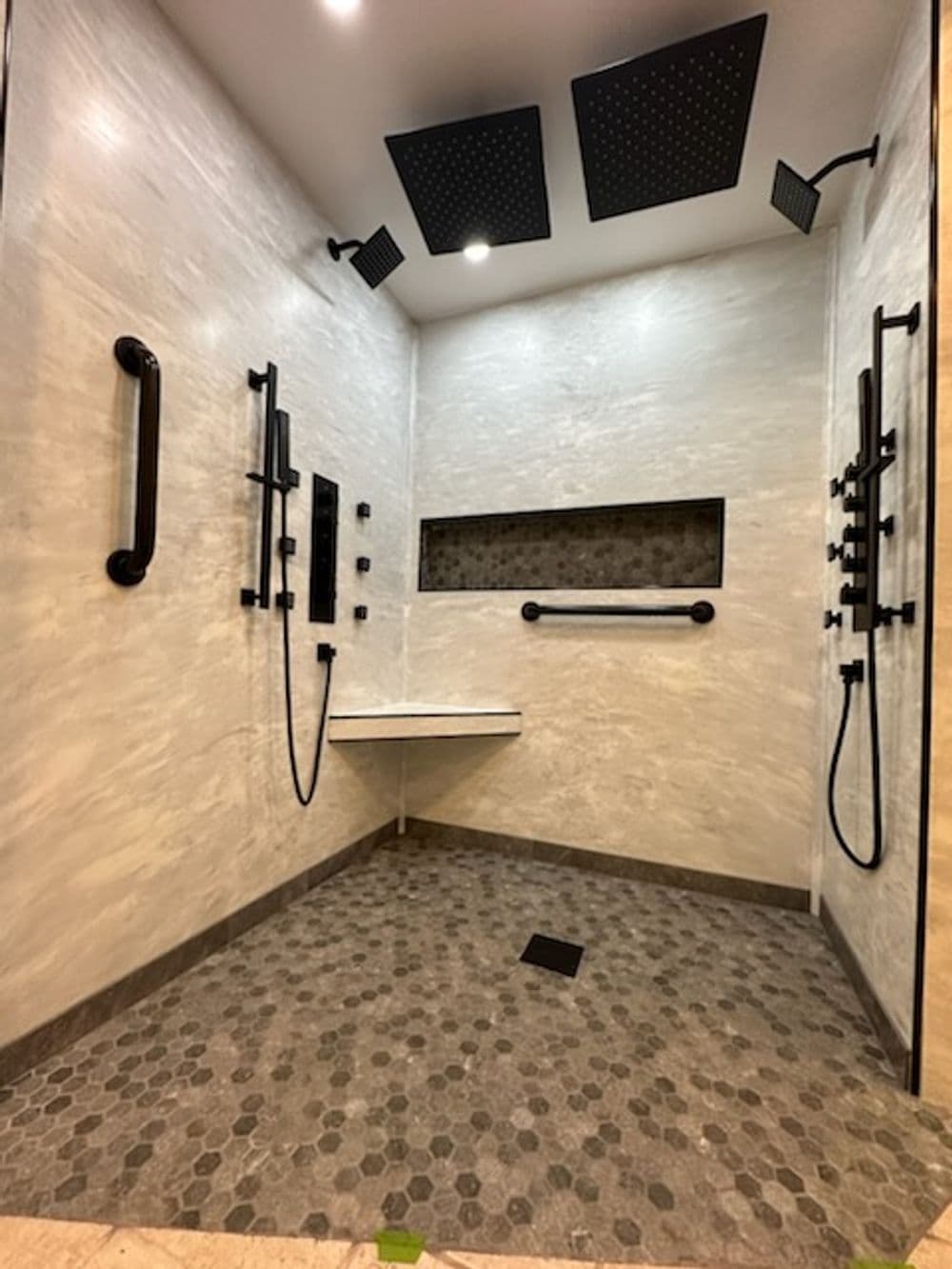 Spacious modern shower with dual rain showerheads and sleek black fixtures.