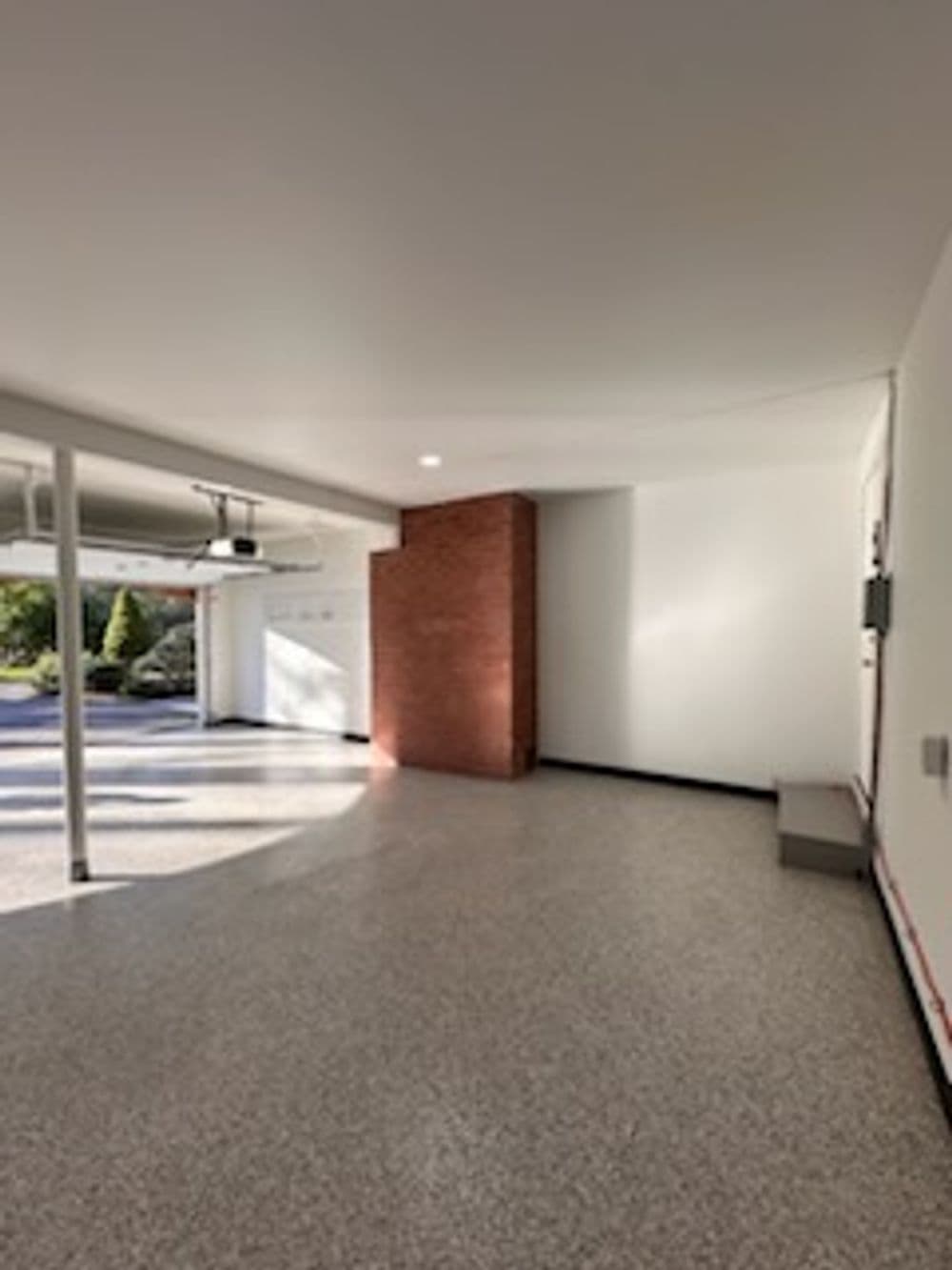 Spacious garage interior with polished floor, brick wall, and ample natural light.