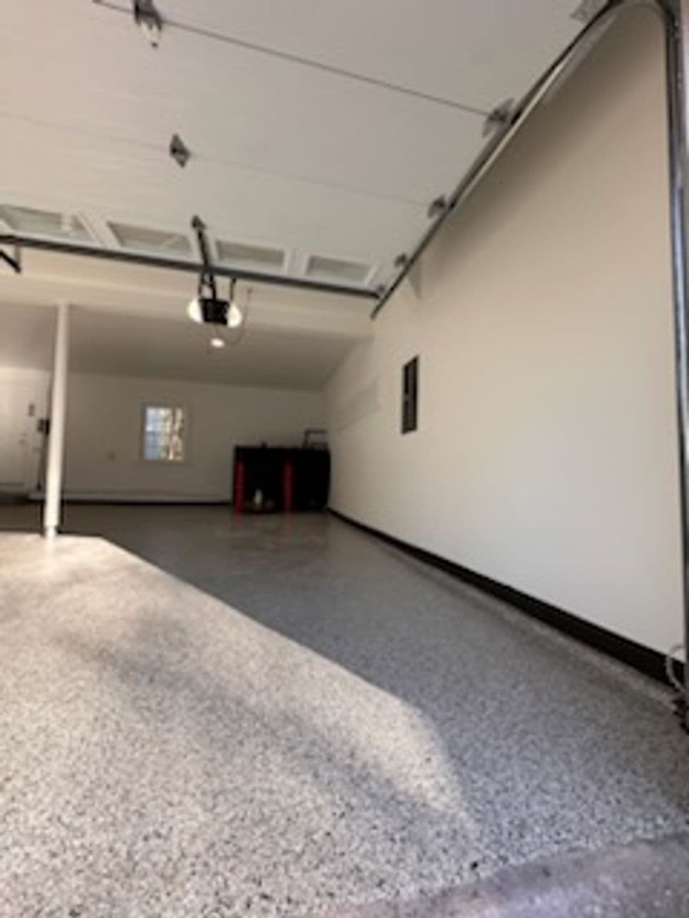 Spacious garage interior with polished floor, wall-mounted storage, and natural light.