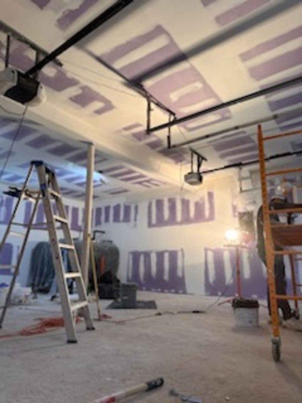 Renovation in progress with a ladder, scaffolding, and purple-painted drywall.