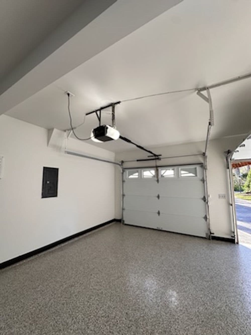 Spacious garage interior with a white door, pendant light, and clean floor.