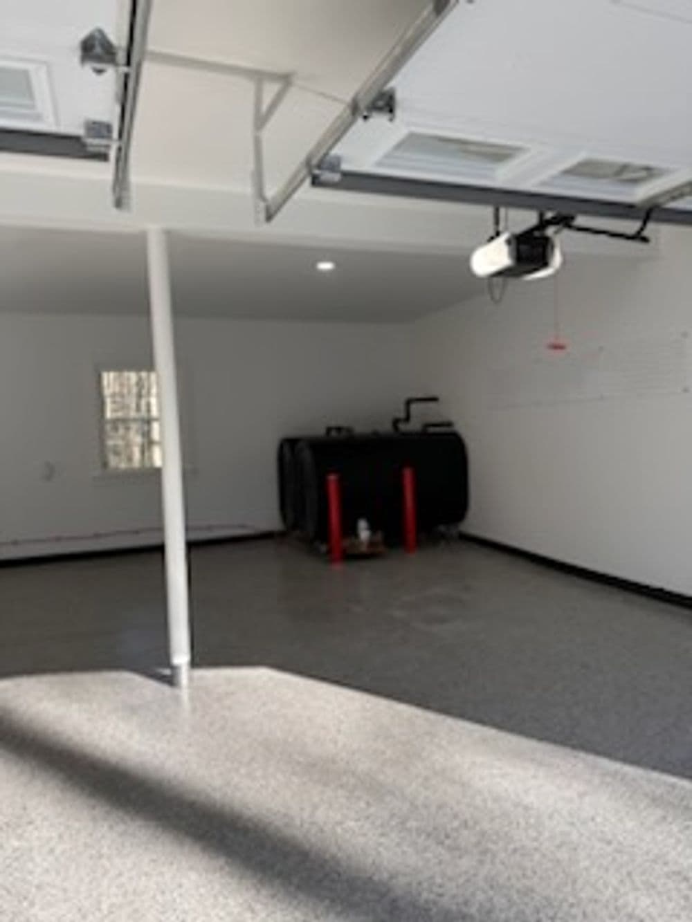 Bright, spacious garage with polished floor, storage tank, and wall-mounted projector.