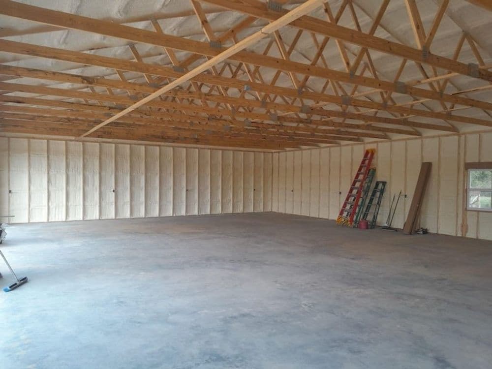 Large empty interior space with wooden beams and insulation, ready for construction.