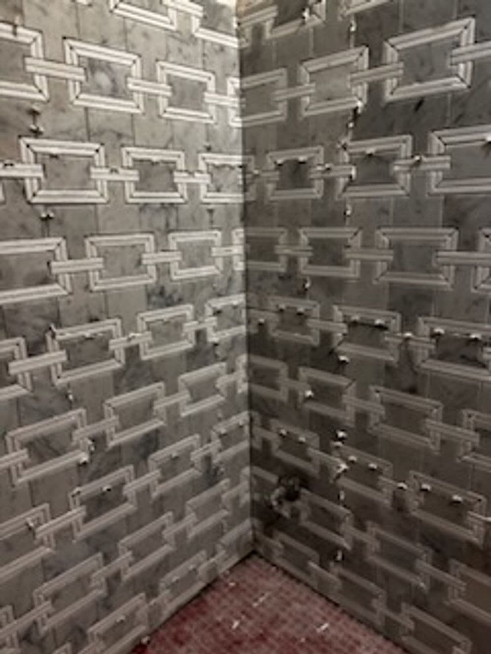 Detailed marble tile wall design in a modern bathroom corner. Elegant geometric pattern.