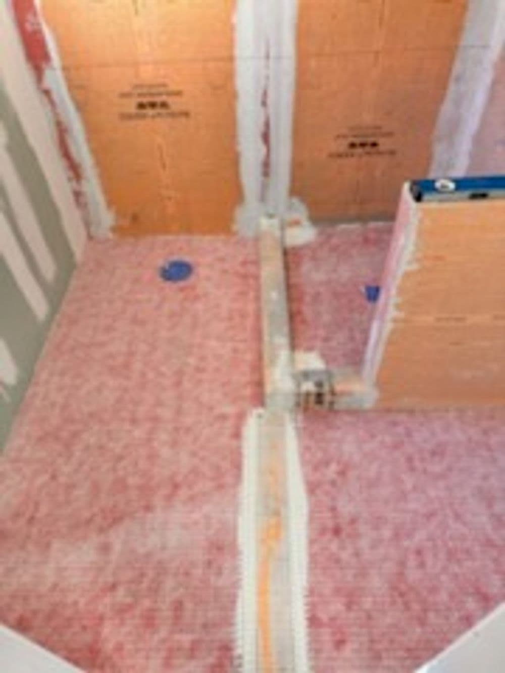 Under-construction bathroom layout with water drainage system and wall preparations.