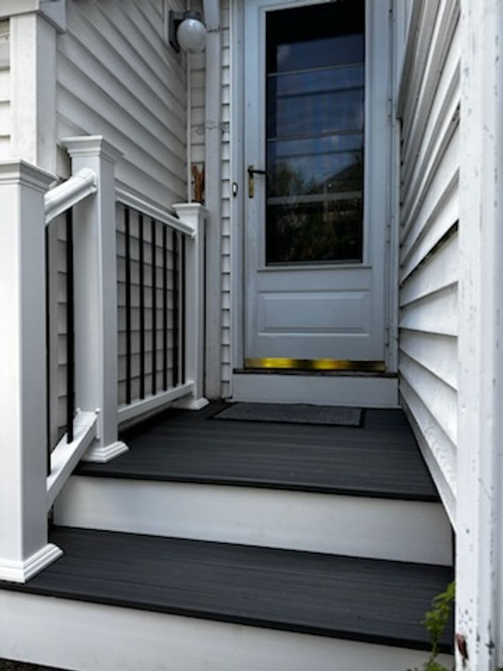 Exterior stairs leading to a white door, with railings and wooden steps.
