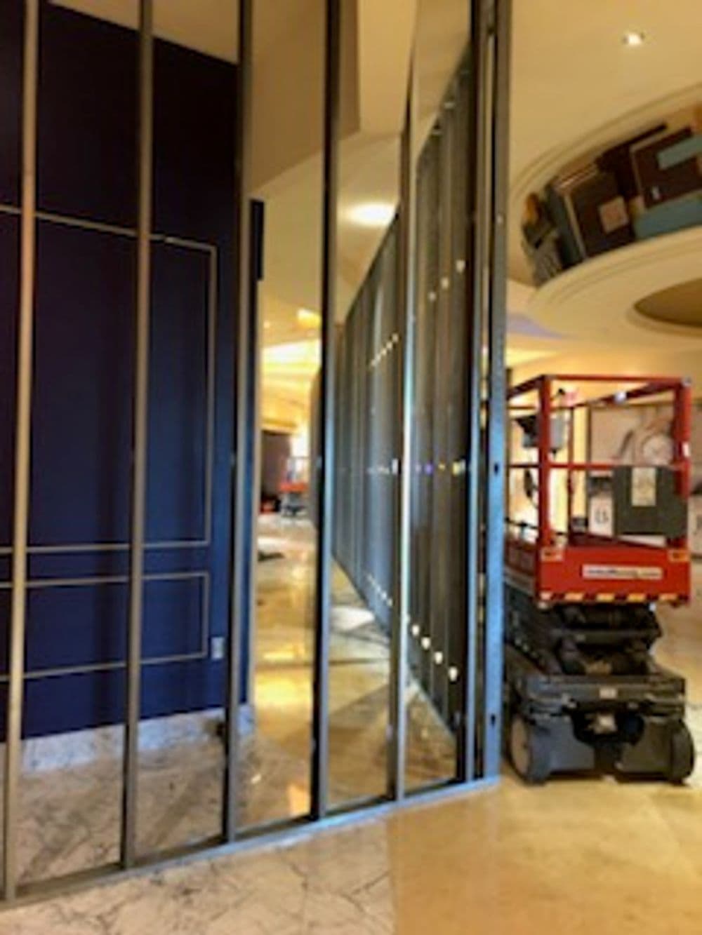 Construction area with a lift near a glass partition in a modern interior space.